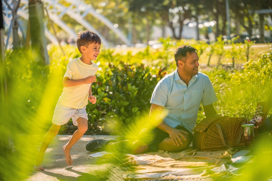 little boy running around playing in public park in sarasota with father