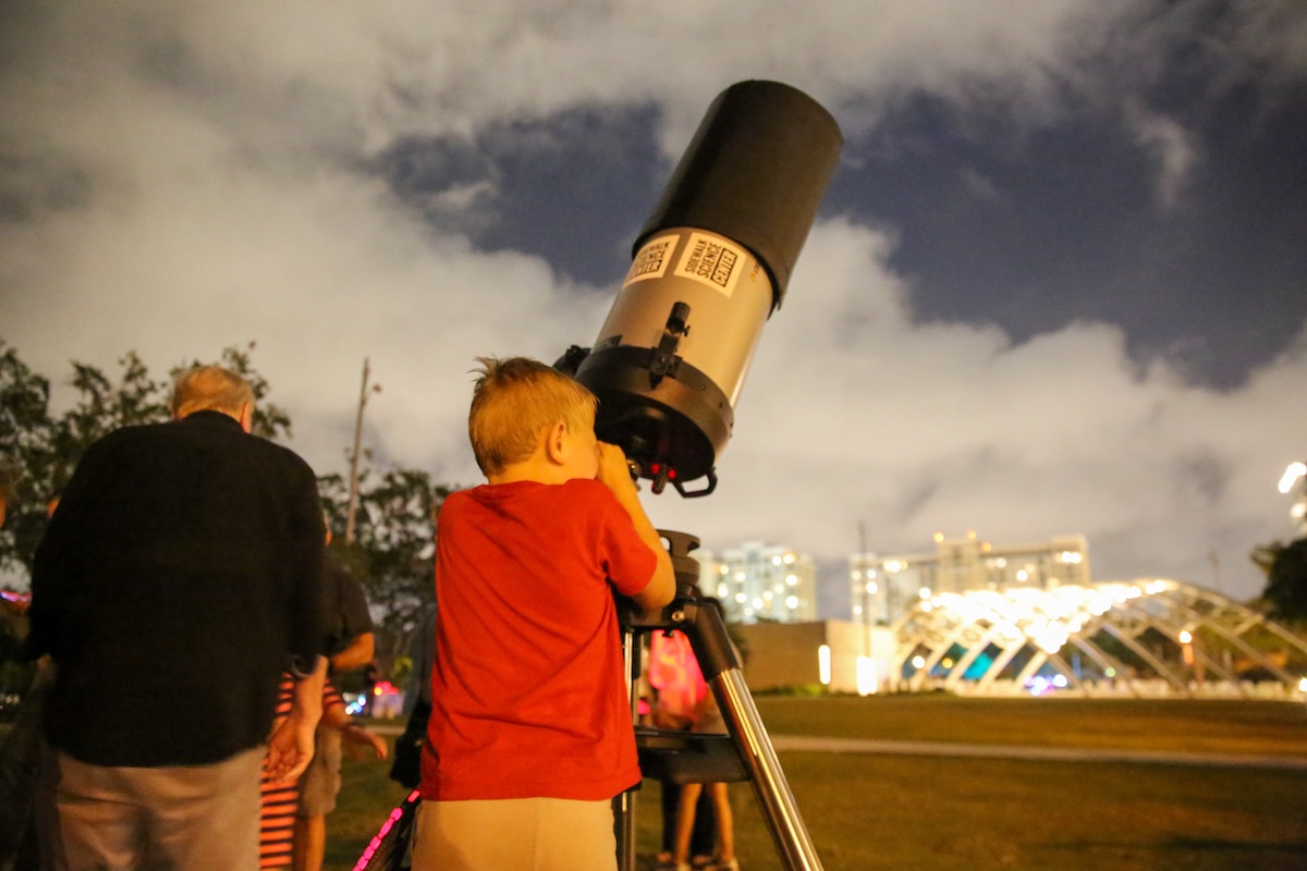 kid looking in microscrope at stars